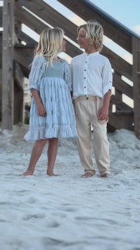 Video of girl wearing Indie Blue Karina Dress Blue Chiffon and Boy wearing Ty Shirt White Linen and Finn Pants walking together on the beach